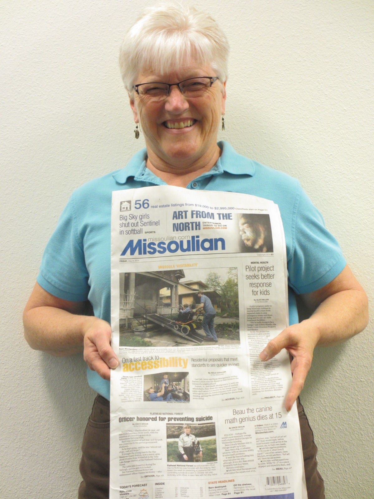 Summit's Jude Monson holding up a Missoulian newspaper showing a story about Visitability on the front page