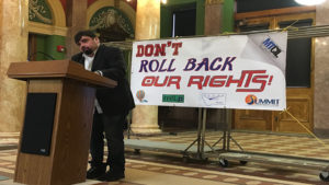 Michael Beers speaking during Rally Day 2017. Don't Roll Back Our Rights banner in the background