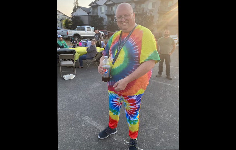 Jason, all dressed in bright tie-dye from head to toe, poses for a picture