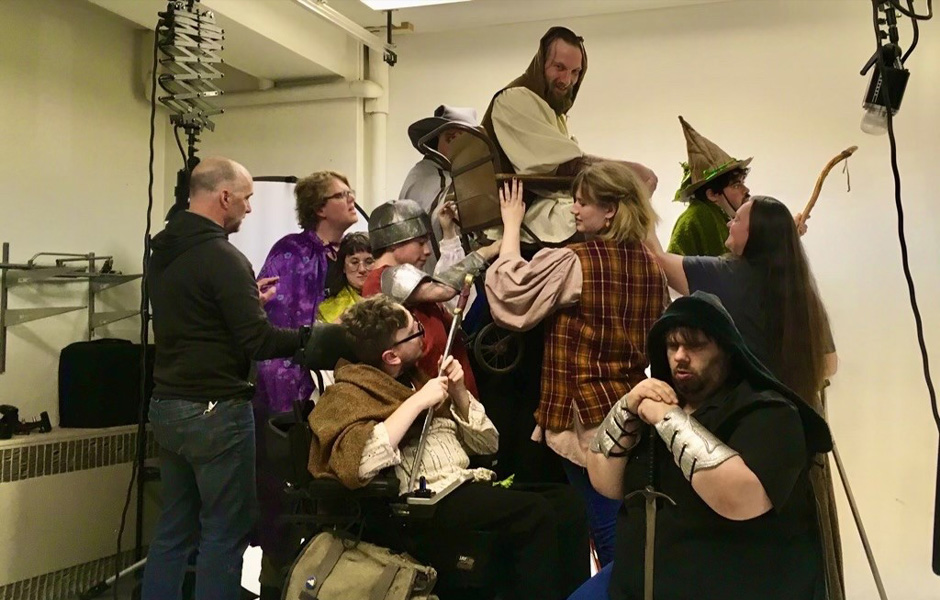 The BASE goers dressed in medieval-looking costumes hold Gavin up in an old wheelchair to pose for a picture