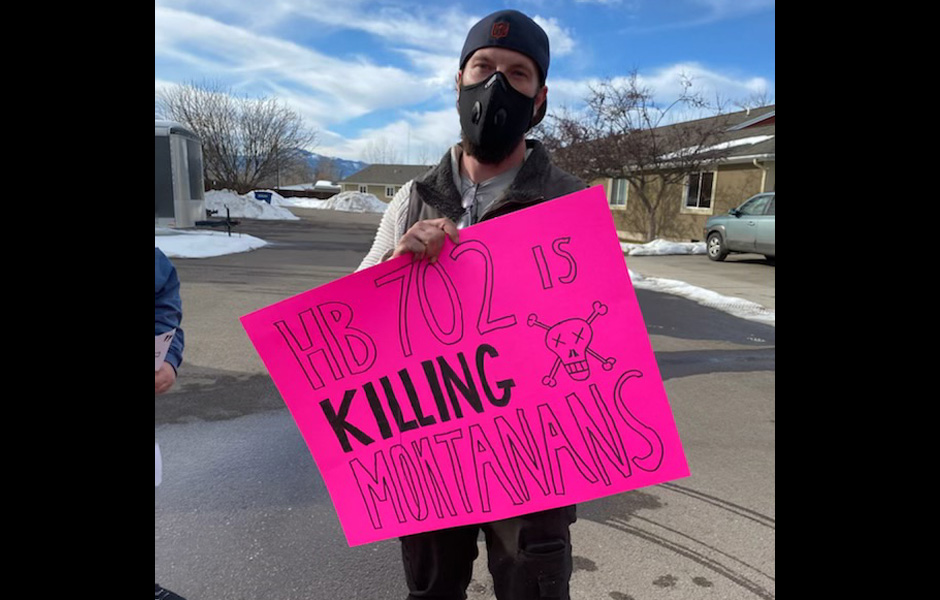 Gavin holds a sign saying "HB 702 is killing Montanans"