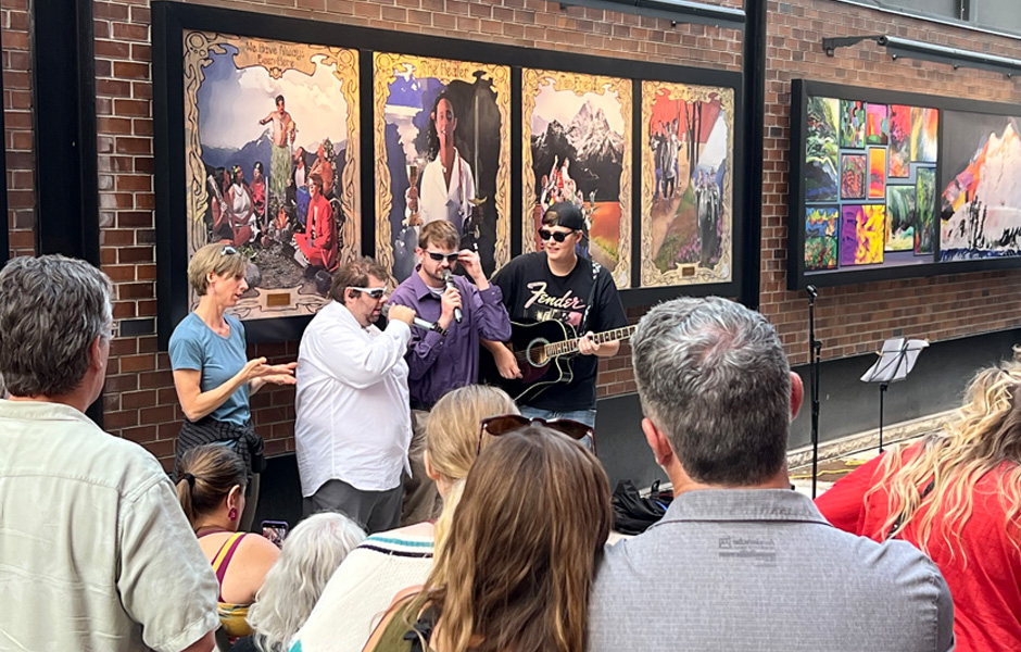 Robby, Tim, and Ethan perform in front of a crowd while Stella interprets via ASL